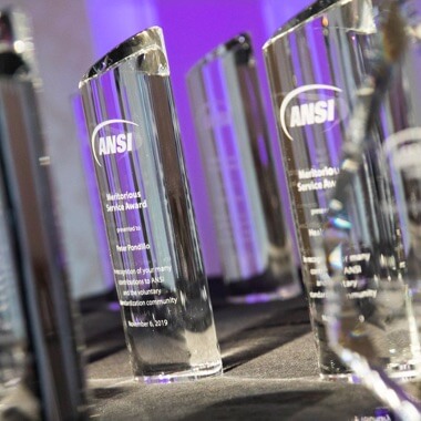A closeup of several clear column crystals engraved for ANSI's leadership and service awards. 