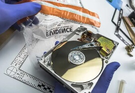 Forensic technician examining a CD in evidence bag