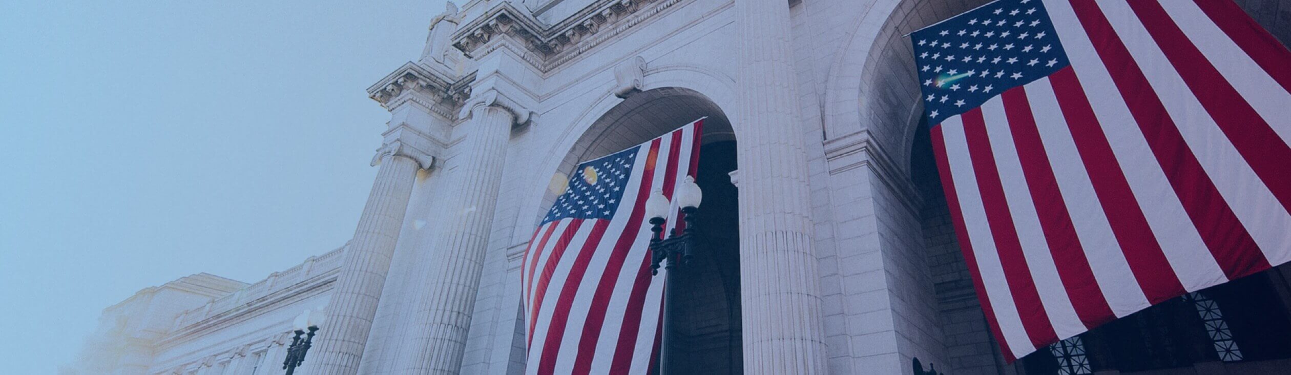 Two large American flags hanging from a U.S. building.