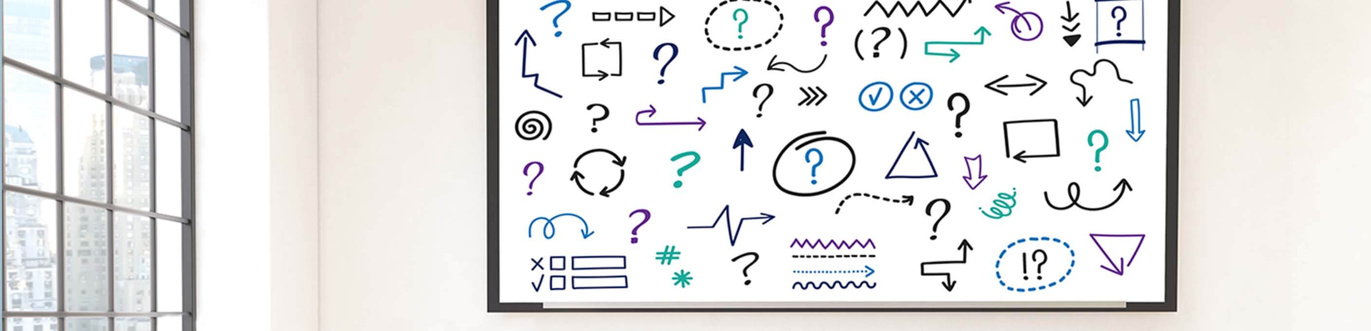 Whiteboard with question marks and symbols written in marker