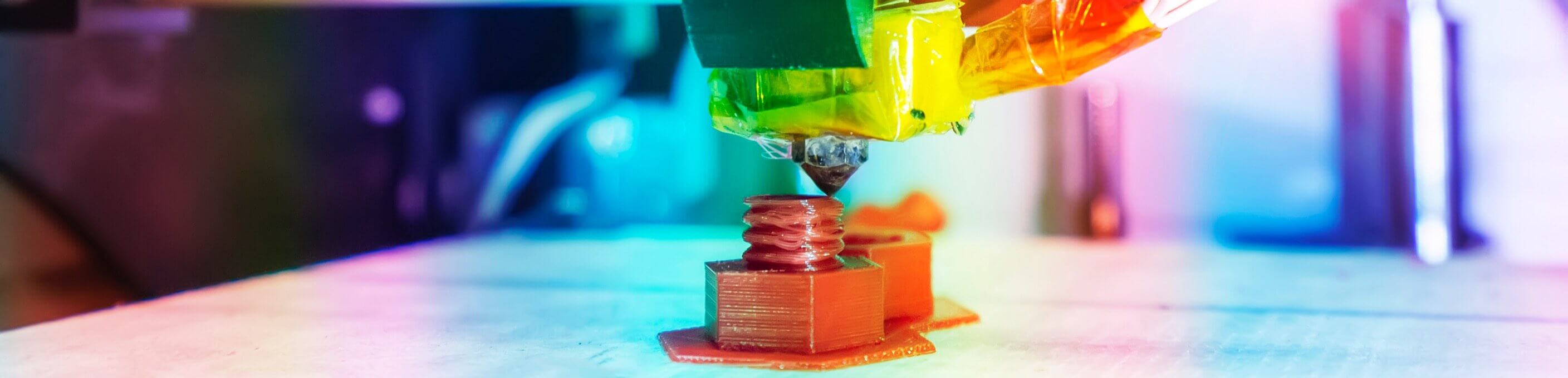 Closeup of a 3D printing machine with a rainbow color tint. 