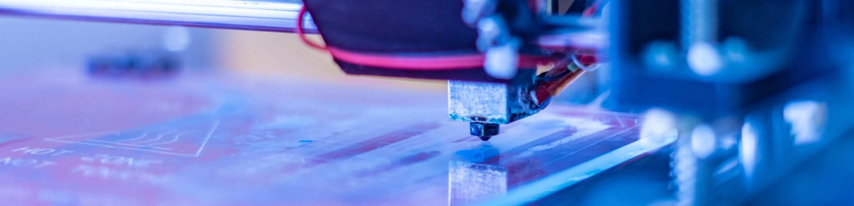 Closeup of a 3D printing machine with a blueish tint. 