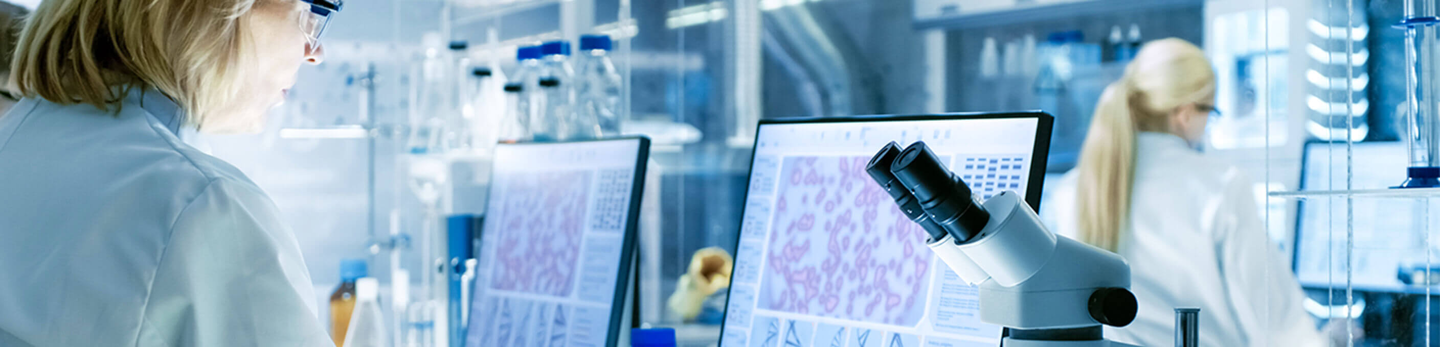 A Caucasian female scientist in a lab looking at nano-particles on a computer screen. 