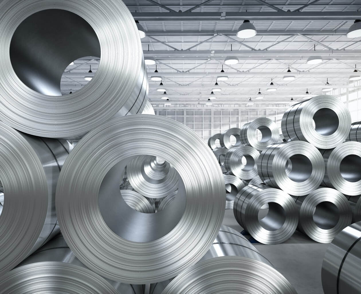 Two large piles of shiny silver industrial metal sheeting material. 