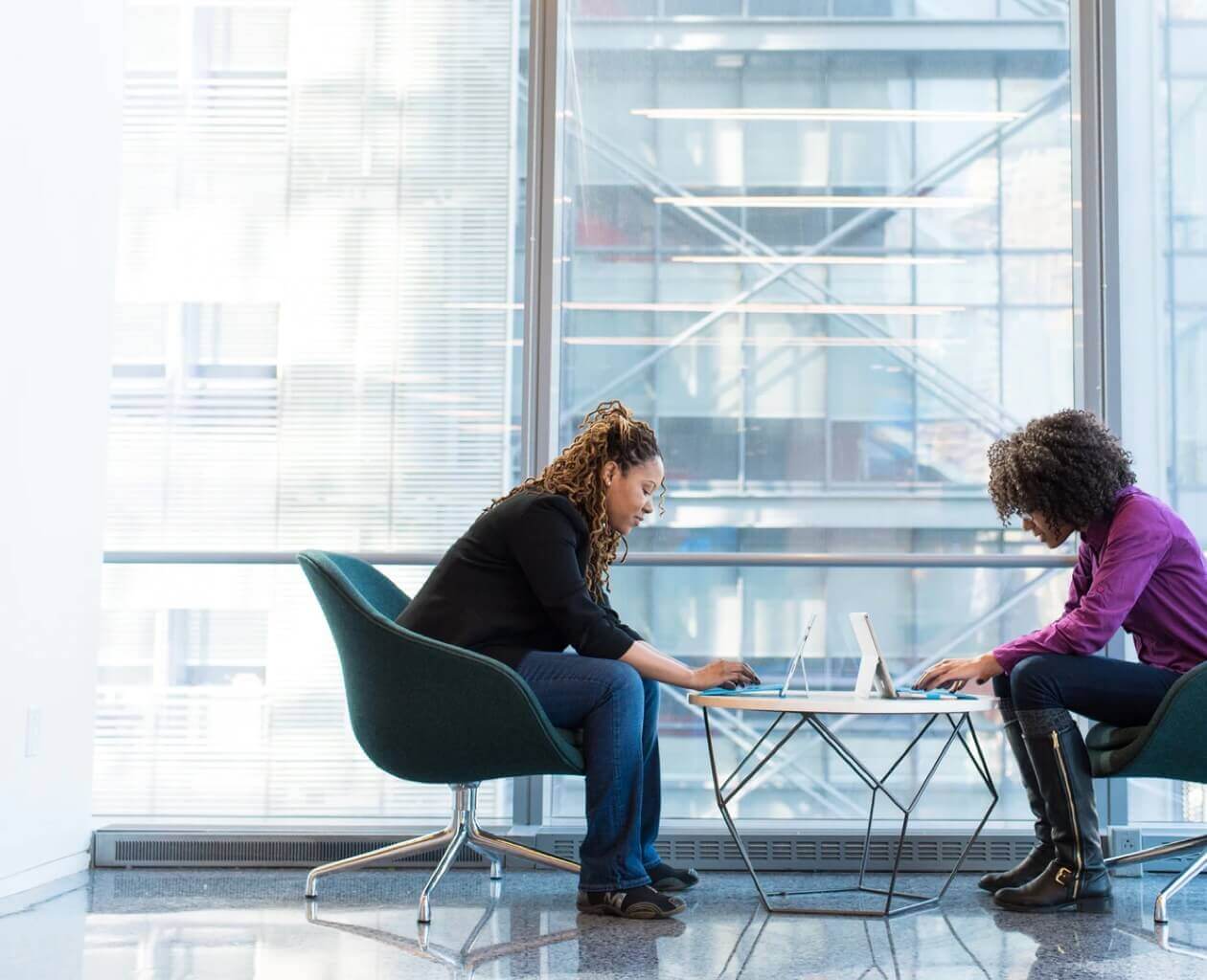 A man and woman seated at a table looking at a computer in a modern office. 