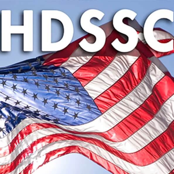 The logo for ANSI's HDSSC program, featuring a close-up American flag waving in the wind against a bright sky.