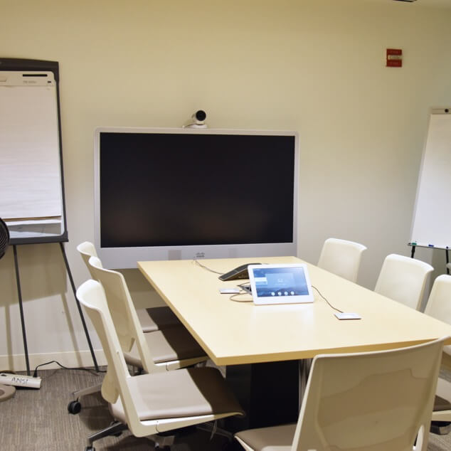 An airy meeting room with a table, chairs, and AV equipment. 
