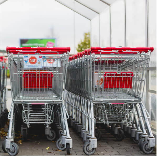 Two rows of red and silver shopping carts pushed together in a supermarket.
