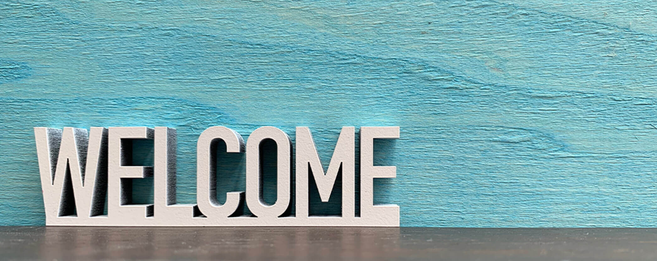 Welcome sign on teal background.